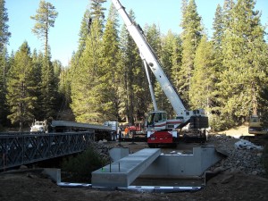 A crane is lifting concrete into the ground.