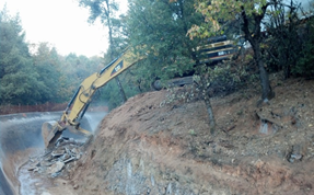 Excavator clearing debris on a hillside.
