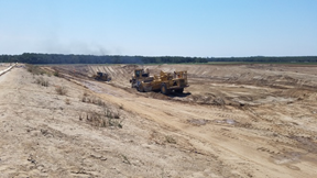 Construction vehicles working in a barren landscape.